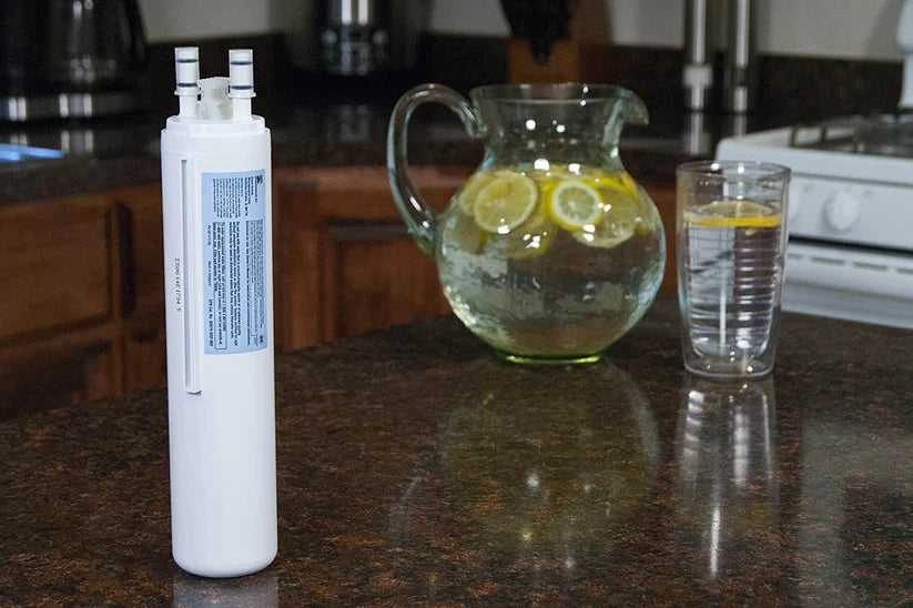Kenmore 9999 water filter beside a pitcher and glass of lemon water on a kitchen counter